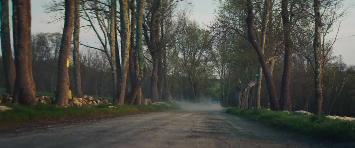 An antique car drives on a rural dirt road