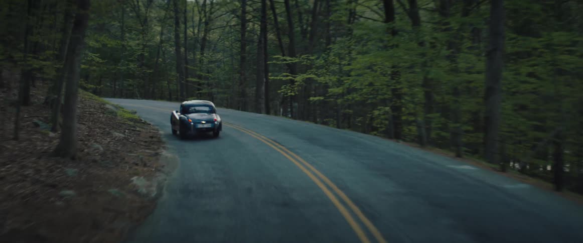 Vintage vehicle driving on a road through the forest at evening