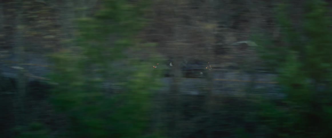 Vintage vehicle driving on a road through the forest at evening