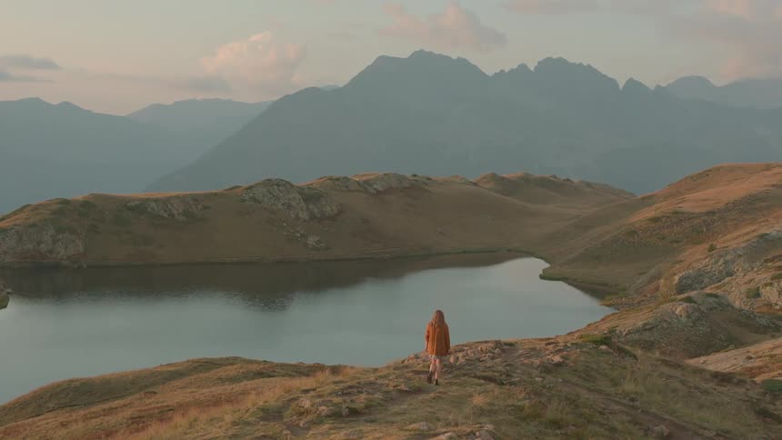 A woman hiking next to a mountain lake in the morning