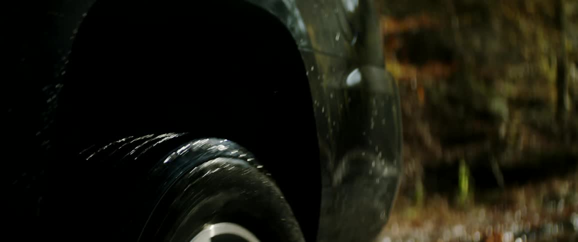 Tire of a car driving over a flooded rural road in the forest