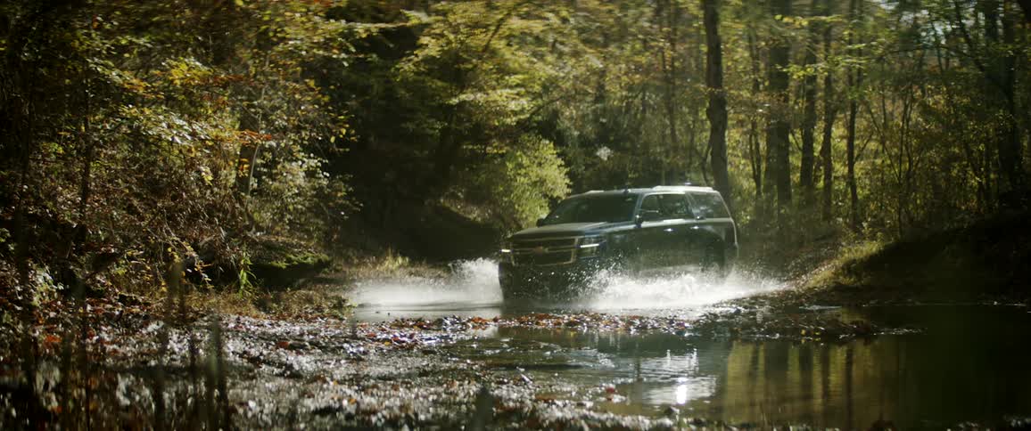 An suv driving through water in a forest