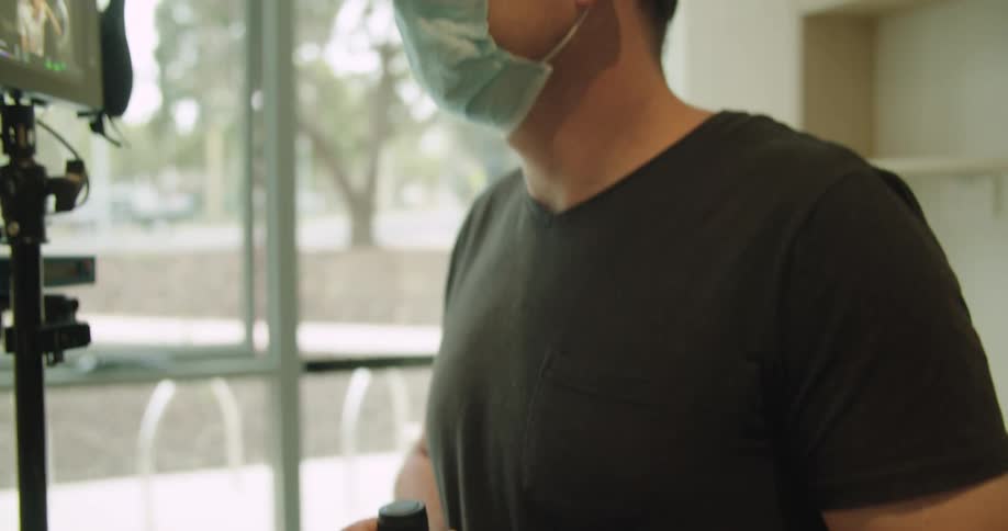 A man uses a controller as he watches and talks to a mounted video display