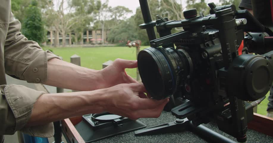 A man adjusting the lens on a film camera mounted on a rig