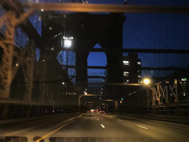 Colorful lights color bridge as traffic heads toward city downtown at night