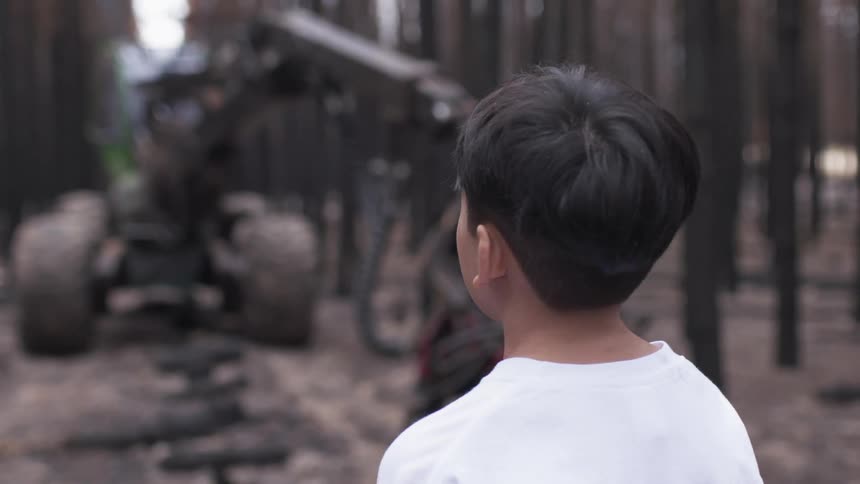 A child is looking at an off road vehicle in the forest