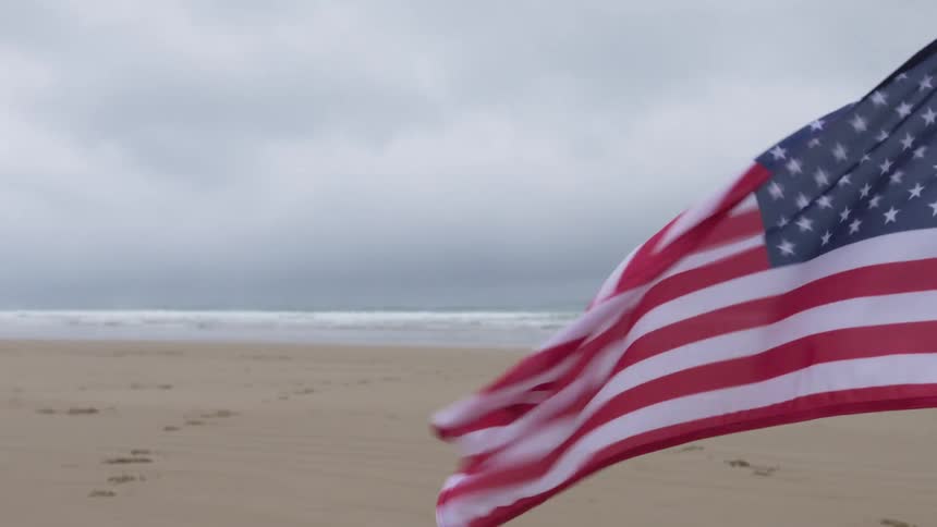 A flag is blowing in the wind at the beach