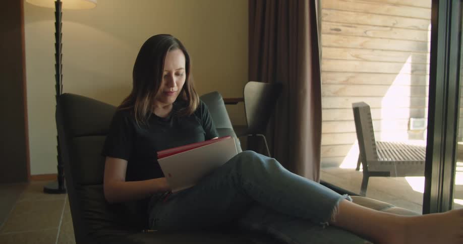 A woman is sitting indoors and writing in a journal