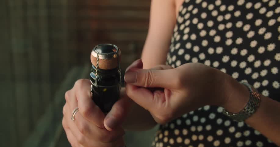 Woman twisting the muselet over the cork of a bottle of champagne