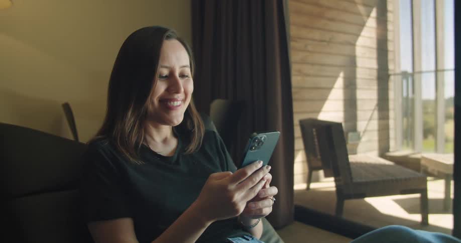 A woman in a room sitting on a couch using a smart phone