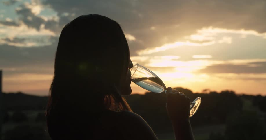 A woman drinking from a champagne glass at sunset