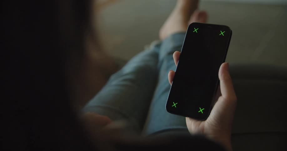 Young woman sitting in a couch at home looking at the screen of a smartphone