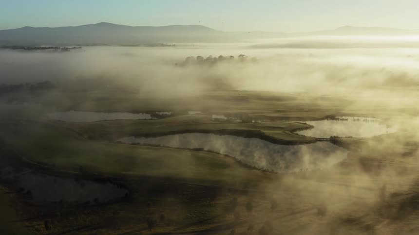 Aerial view of the lakes near the mountains under the fog at sunset