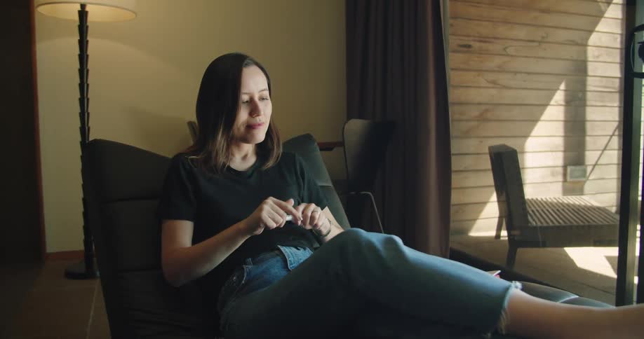 A woman relaxing in a chair puts her notebook and pen away and picks up her phone
