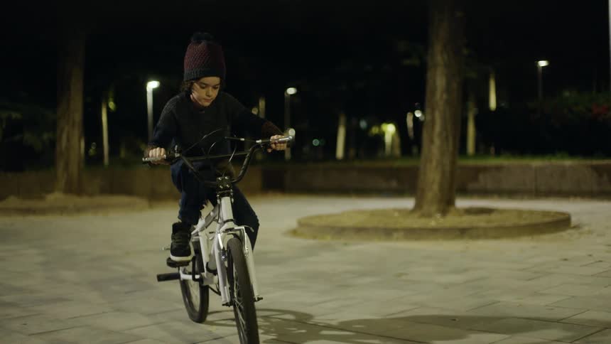 A child is riding a bike outdoors at night