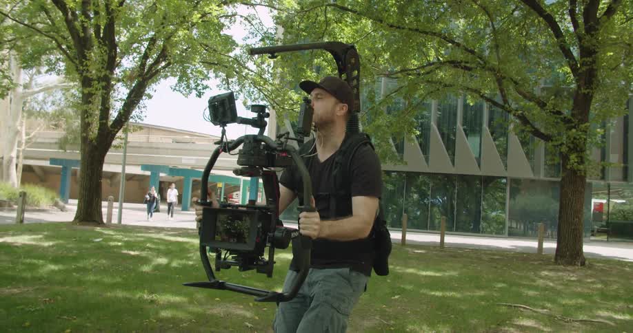A man is using a rig to record film outside