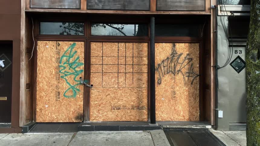 Graffiti is written on a door of a store in a city