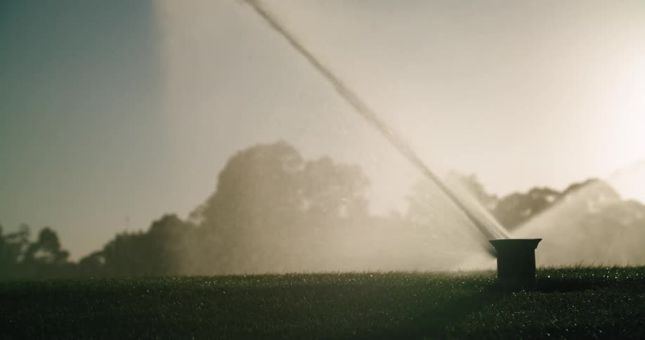 Close up of a sprinkler head watering the lawn at a park