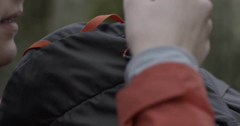 A woman is zipping shut her backpack