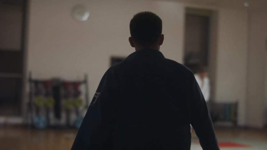 Silhouette of a man wearing judo uniform walking towards a gym