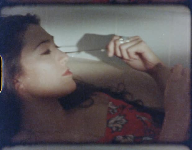 Woman with dark hair and a red dress lies in a bathtub