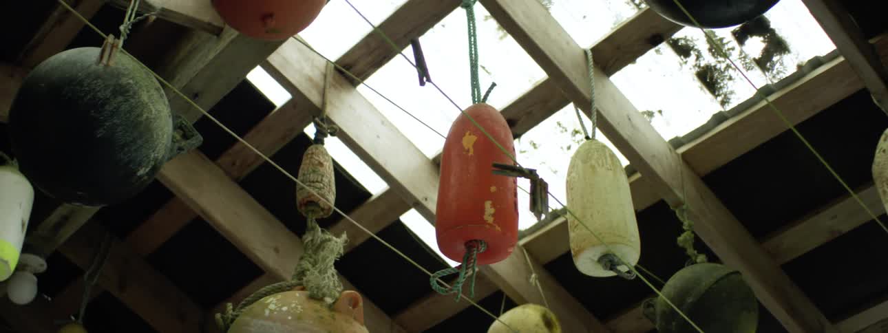 A ceiling with lanterns and balls hanging with ropes from wooden beams