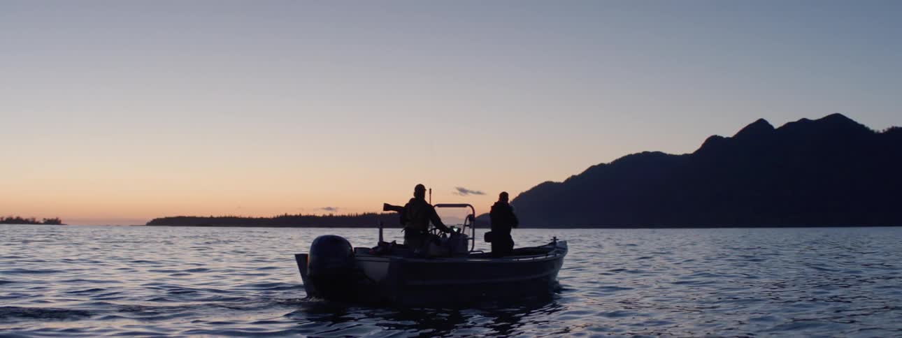 Two people are moving on a boat at sunset