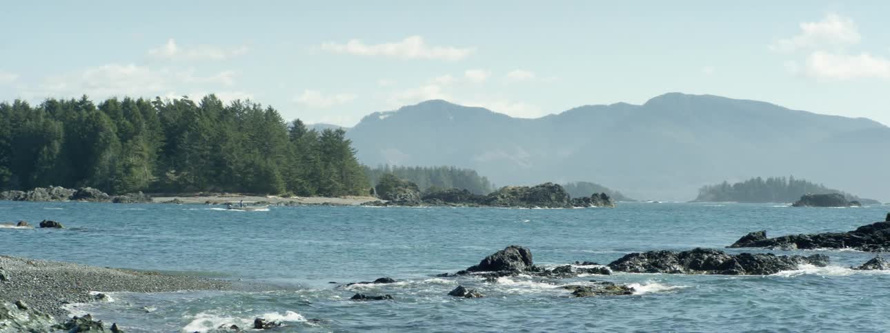 Small waves on the blue calm water of a lake in the pine tree forest near the mountains