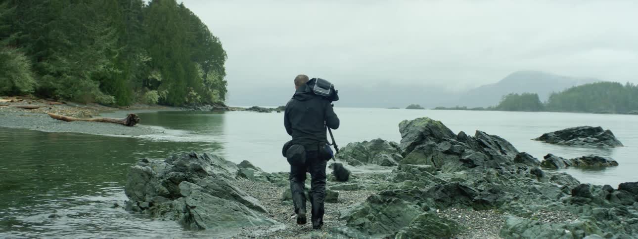 A man walks up to the river and sets up his camera