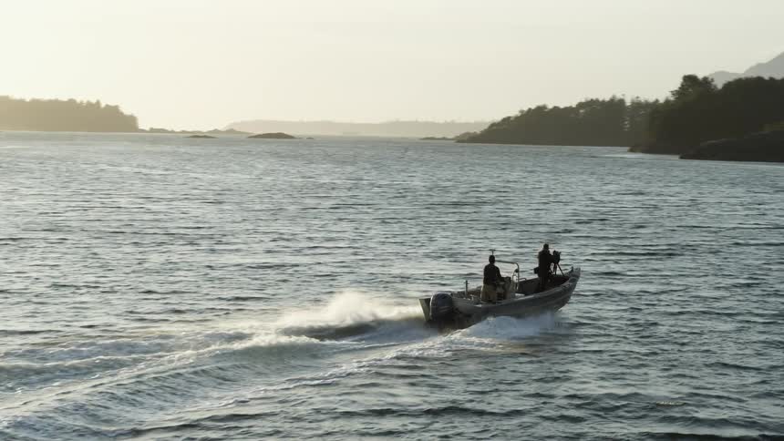 Two people in a speed style boat across a lake with land all around them