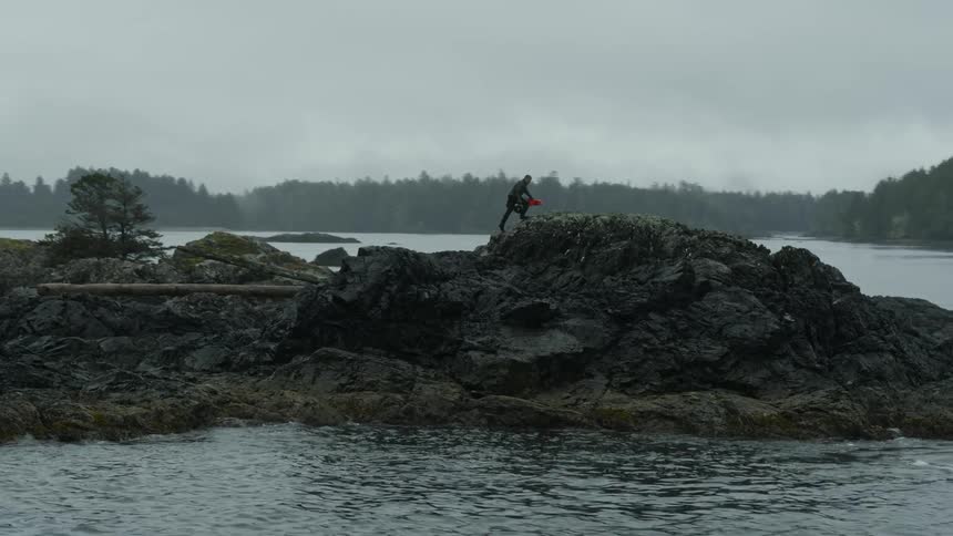 A man climbs up and walks across a cliff on the shore
