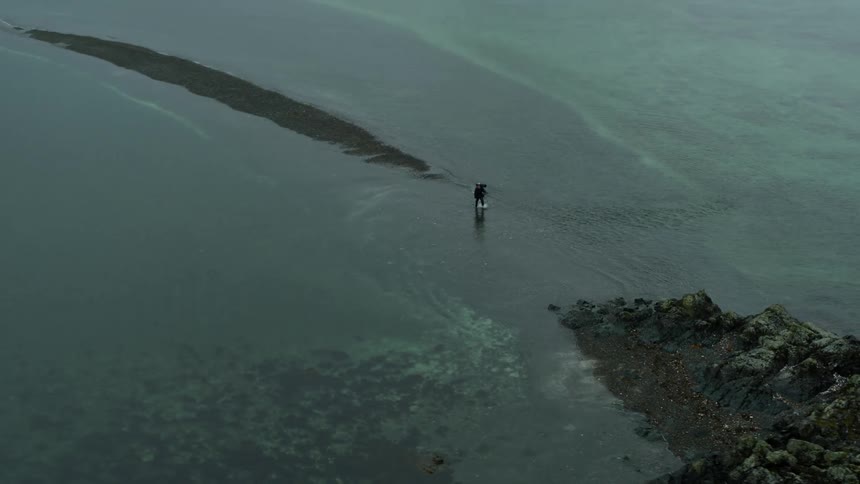 A person walking on a shore with water