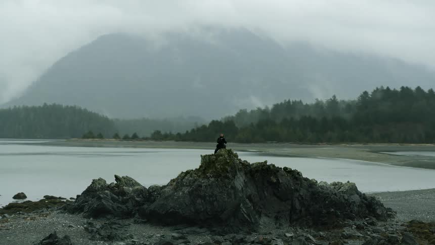A person is standing outdoors near the coast