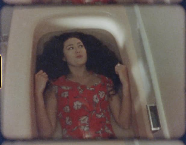A fully clothed woman lying in a bathtub full of water
