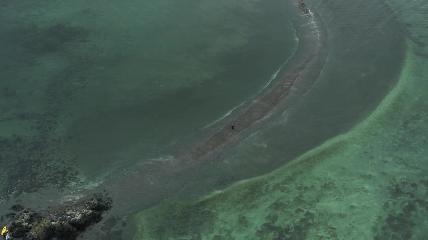 A small boat near rocks on shore as green water ripples