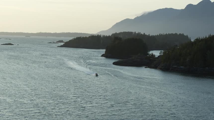 A boat is on the water with mountains in the background
