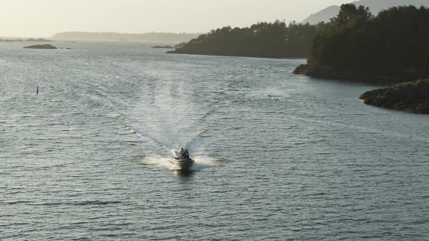 A boat traveling on a lake near the pine tree forest in the mountains at sunset