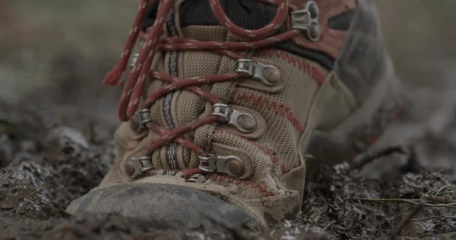 A hiking boot steps in squishy mud