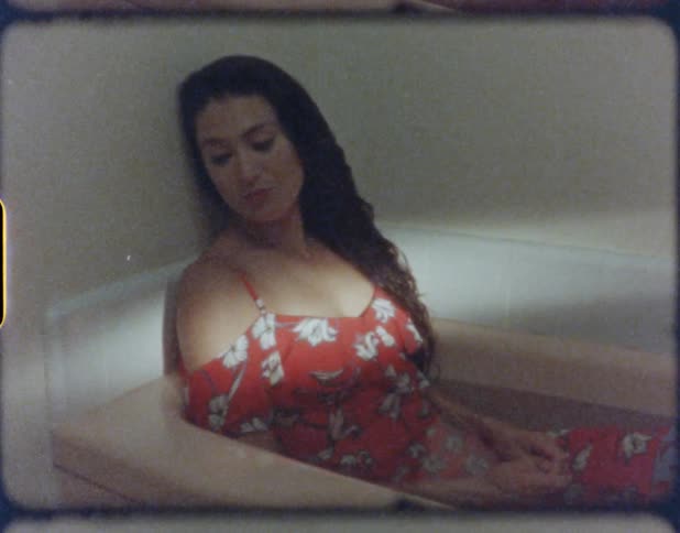 A woman with a dress sitting in a bathtub with water