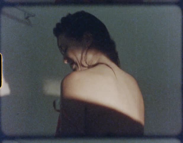 A woman laughs as she removes her dress at home