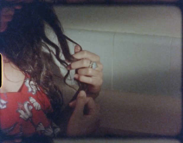 A woman is touching her hair while standing indoors