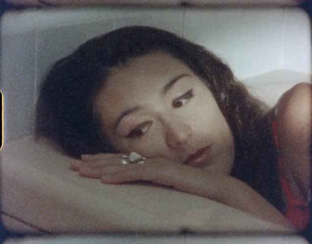 Vintage film of a young woman laying on an empty bath tub modeling