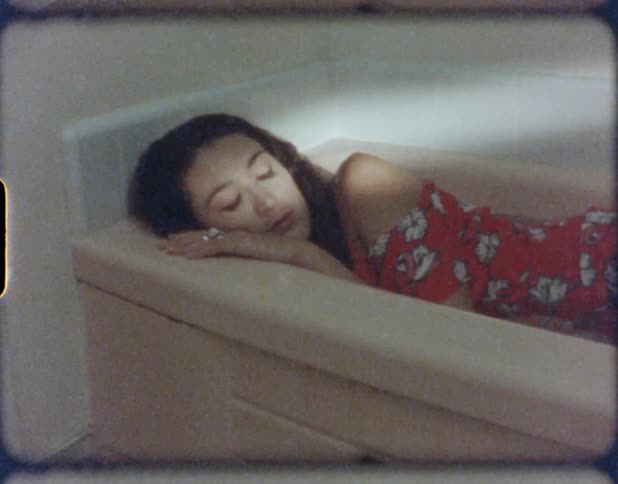 Young girl in a red dress resting inside a bathtub in the bathroom