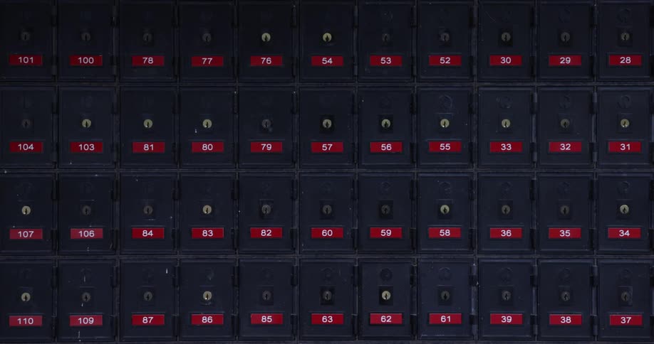 Keyholes on the doors of small numbered mailbox lockers