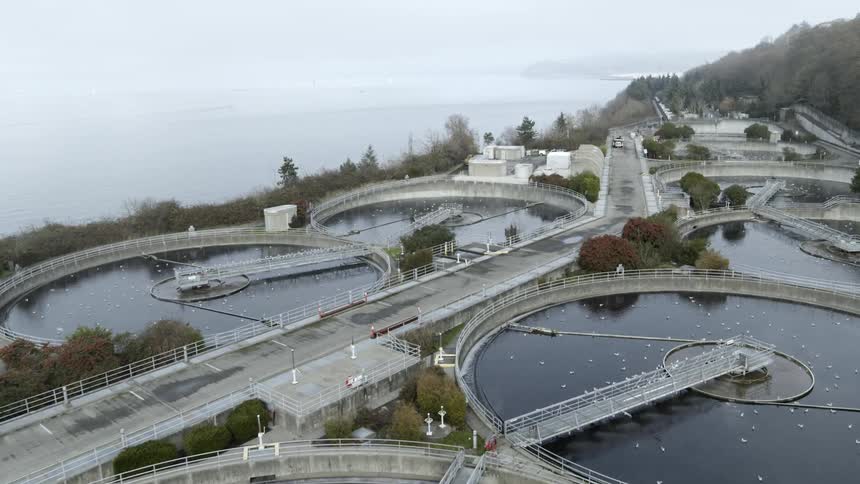 Pushing through fog and steam to reveal multiple wastewater tanks at a sewage treatment facility