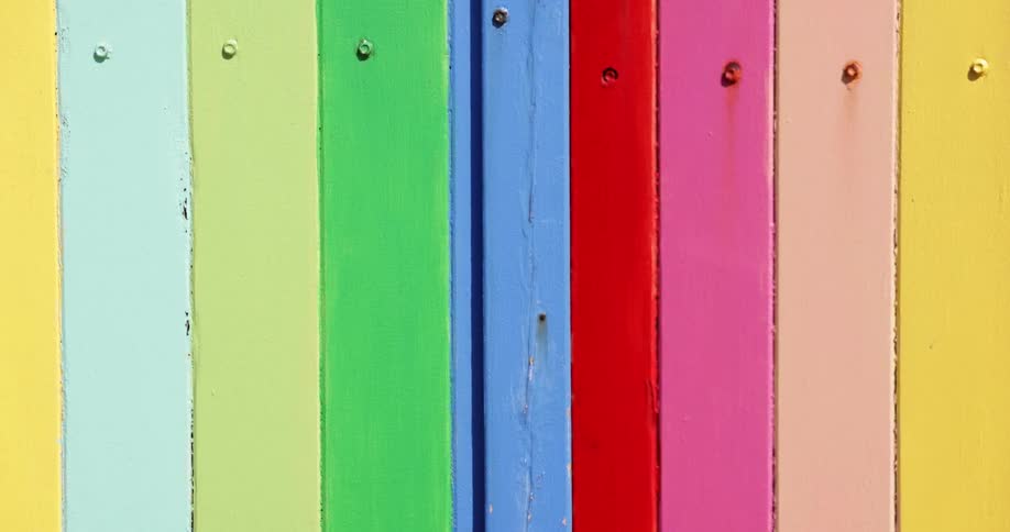 Wood slats are painted in bright colors with rust coming from some of the screws