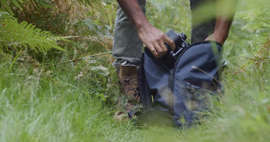 A hiker takes a camera out of his backpack