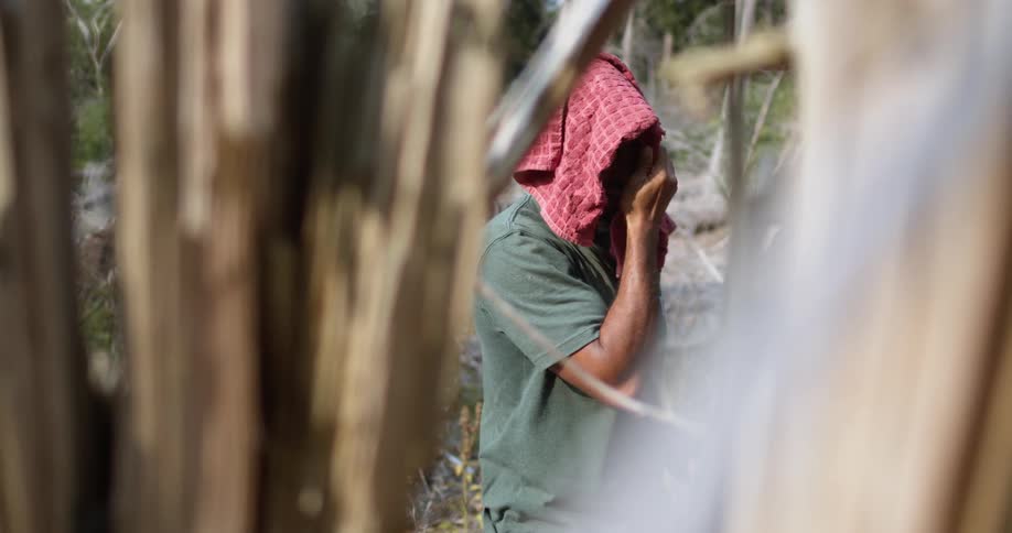 A bald male pauses to wipe the sweat from his head and face with red cloth