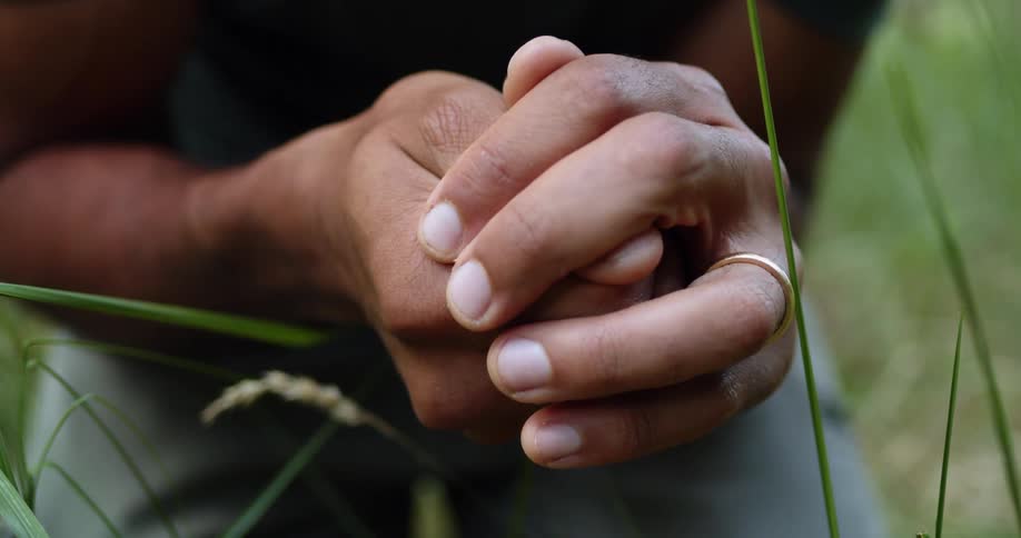 A man opens his hands to reveal a small frog then closes his hands again