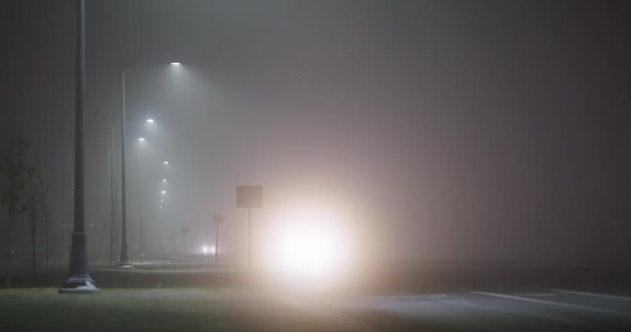 Traffic travels along a road on a dark and misty night
